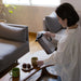 Woman in a living room pouring coffee into a mug.