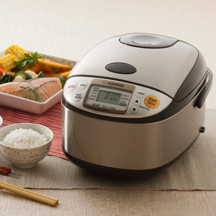 Zojirushi rice cooker on a table with food items in the background
