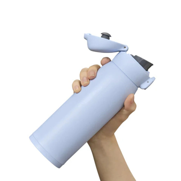 Hand holding a light blue water bottle with a black cap on a white background