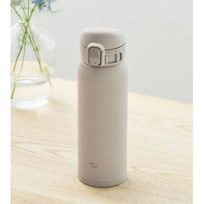 Beige thermos bottle on a wooden surface with a light gray background