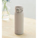 Beige thermos bottle on a wooden surface with a light gray background