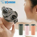 Zojirushi travel mug with a person holding it, and three other mugs in different colors on a white background.