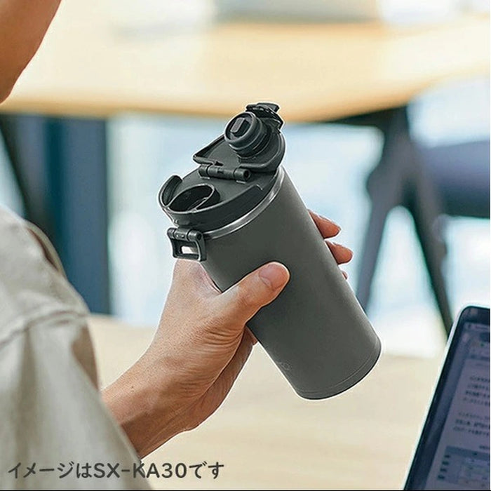 Person holding a gray water bottle with a black lid in an office setting