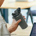 Person holding a gray water bottle with a black lid in an office setting