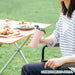 Person holding a pink insulated mug outdoors at a picnic table.