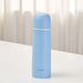 Blue thermos bottle on a white surface with a light curtain background
