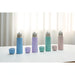 Set of colorful water bottles and cups on a white surface with a light curtain background
