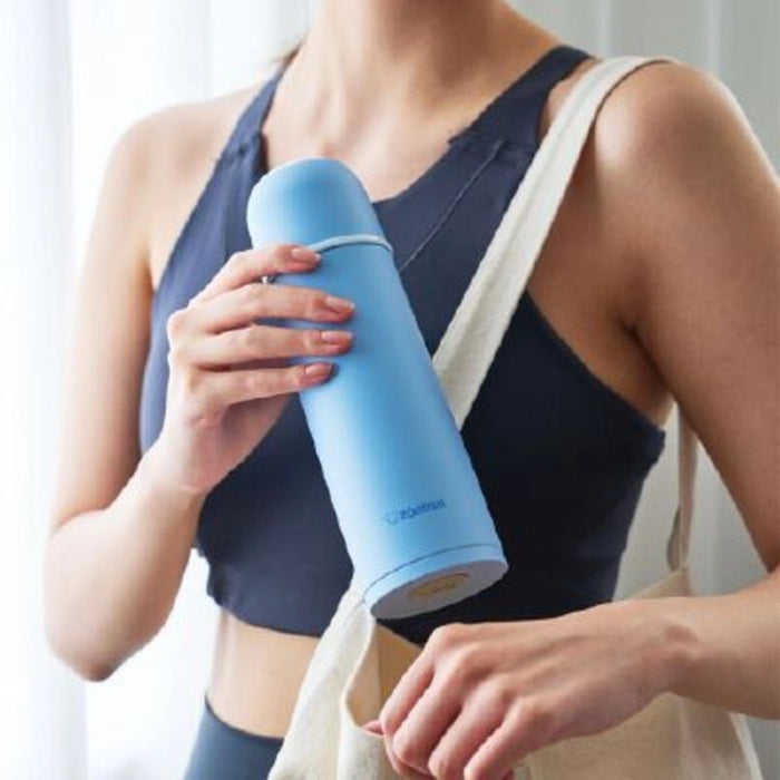 Person holding a blue cylindrical product with a strap over shoulder