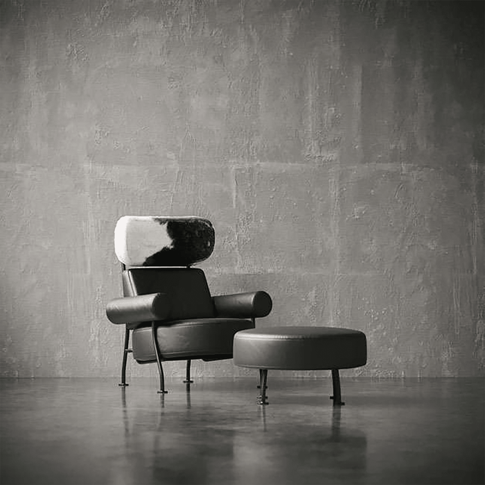 Modern armchair with ottoman against a textured gray wall