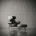 Modern armchair with ottoman against a textured gray wall