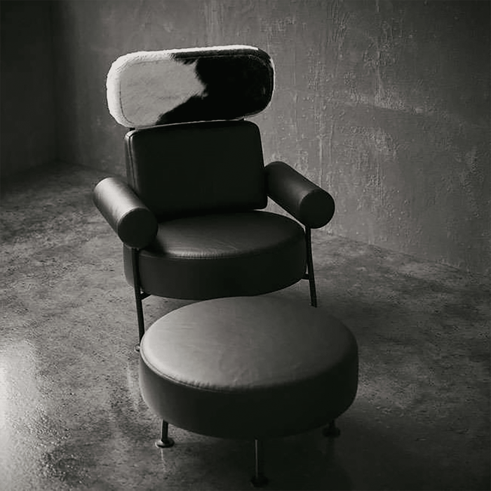 Modern black chair with cowhide pattern backrest in a dimly lit room.