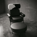 Modern black chair with cowhide pattern backrest in a dimly lit room.
