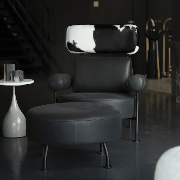 Black leather armchair with cowhide pattern backrest in a dimly lit room.