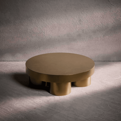 Bronze-colored round table with unique cylindrical legs on a textured gray background