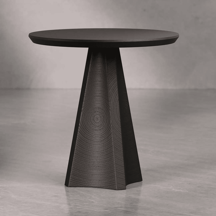 Modern black side table with a textured base on a gray floor.