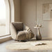 Modern armchair in a stylish room with a side table and abstract art.