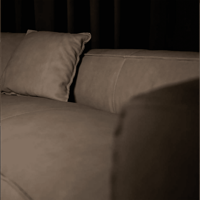 Brown sofa with a pillow against a dark background