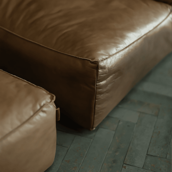 Brown leather ottoman on a wooden floor