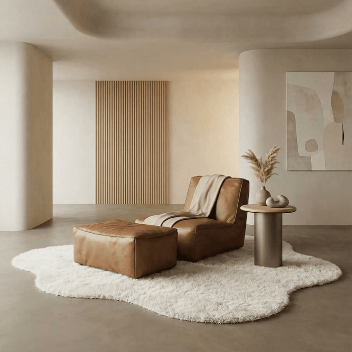 Modern living room with brown leather sofa, ottoman, and side table on a white rug.