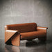 Brown leather sofa against a textured gray wall
