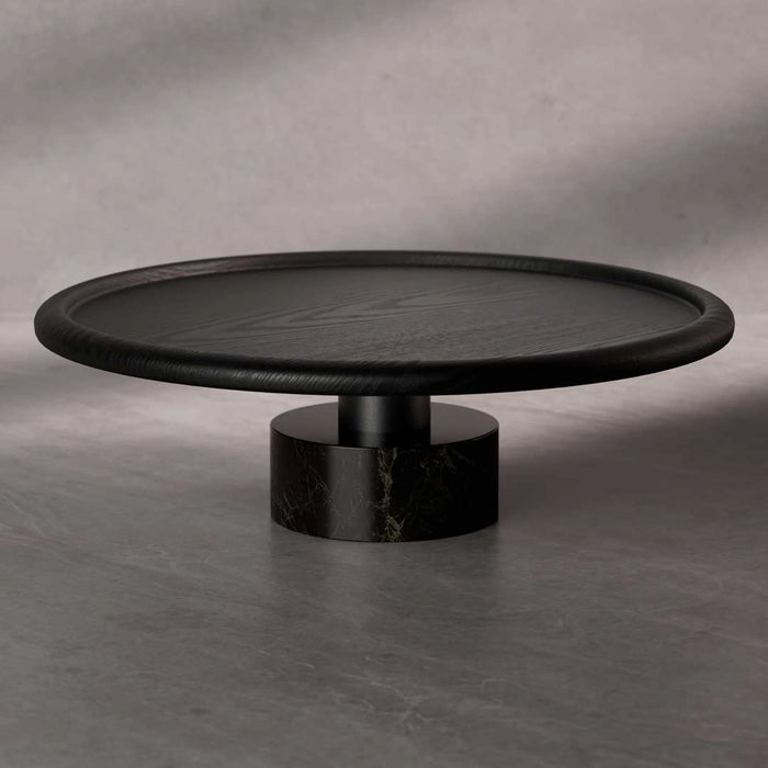 Black round coffee table on a gray concrete floor