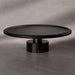Black round coffee table on a gray concrete floor