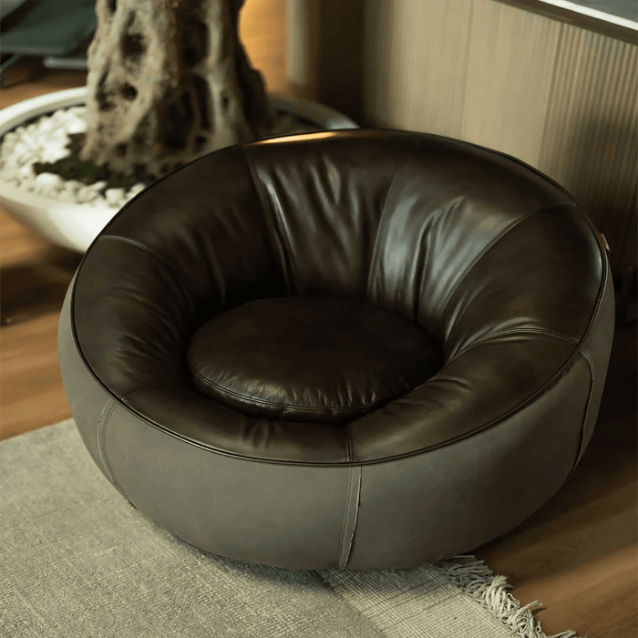 Brown leather chair on a wooden floor with a decorative plant in the background