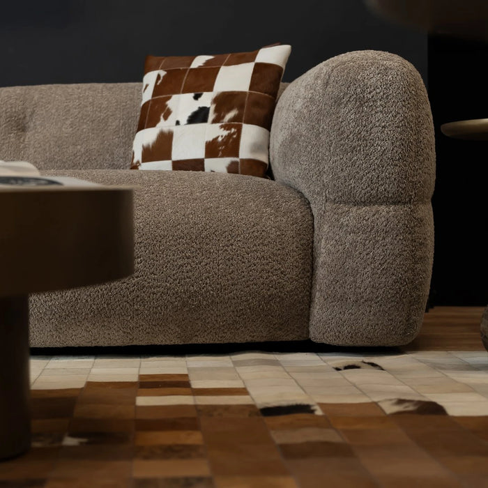 Brown textured sofa with a checkered pillow on a patterned rug