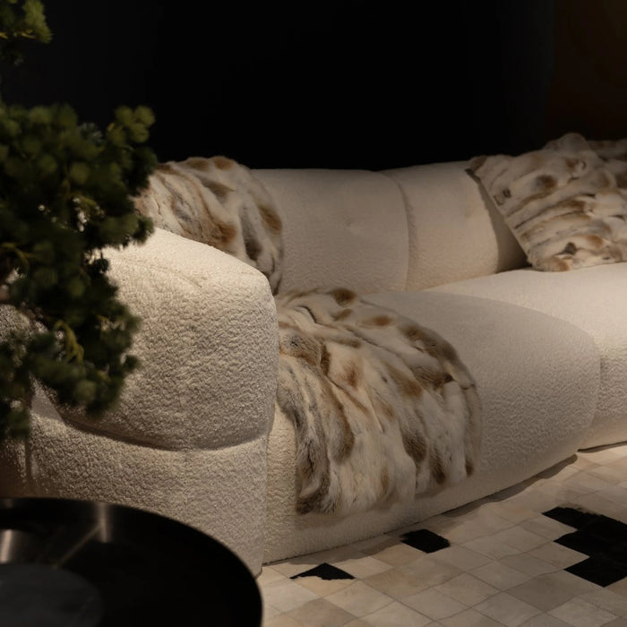 White textured sofa with animal print cushions in a dimly lit room.