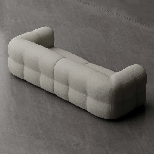 Modern, tufted sofa in a neutral color on a gray concrete floor.