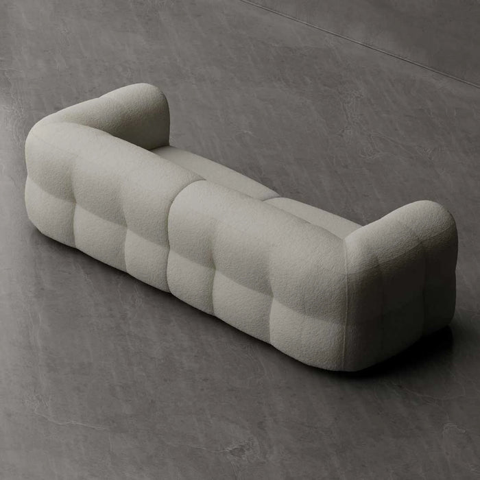 Modern, tufted sofa in a neutral color on a gray concrete floor.