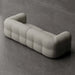 Modern, tufted sofa in a neutral color on a gray concrete floor.