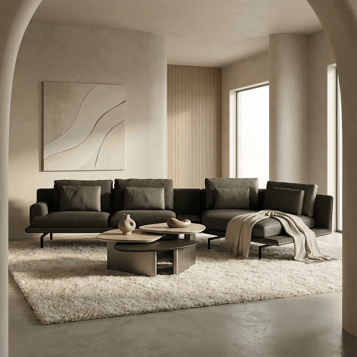 Modern living room with a gray sectional sofa, round coffee table, and abstract art on the wall.