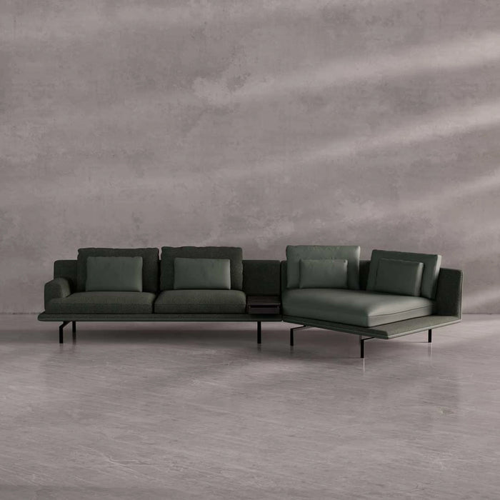 Modern green sectional sofa against a gray concrete wall.