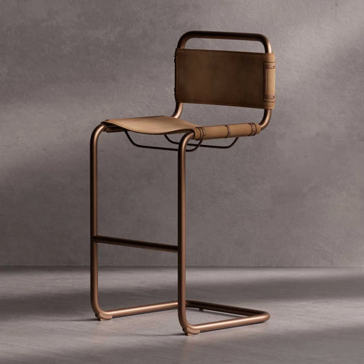Bronze bar stool with leather seat against a gray background
