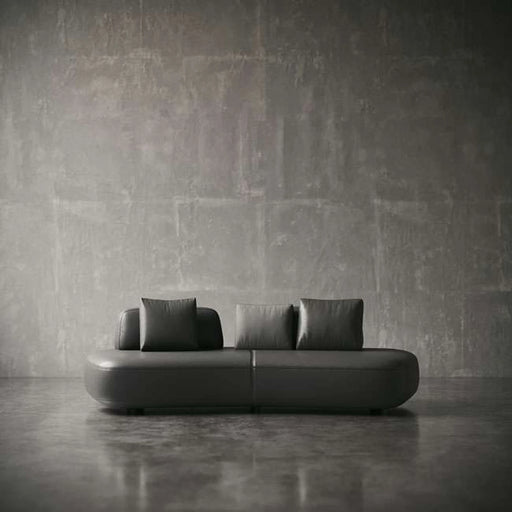 Modern black sofa against a textured gray wall