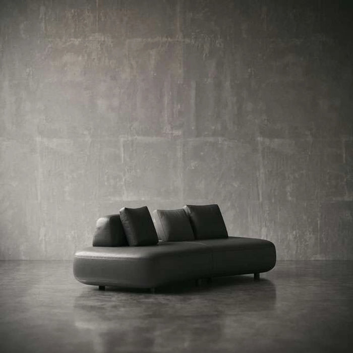 Modern black sofa against a textured gray wall
