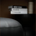 Close-up of a gray leather armchair with a blurred background featuring books.