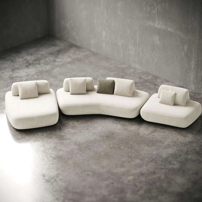 Modern white sofa with gray cushions on a concrete floor.