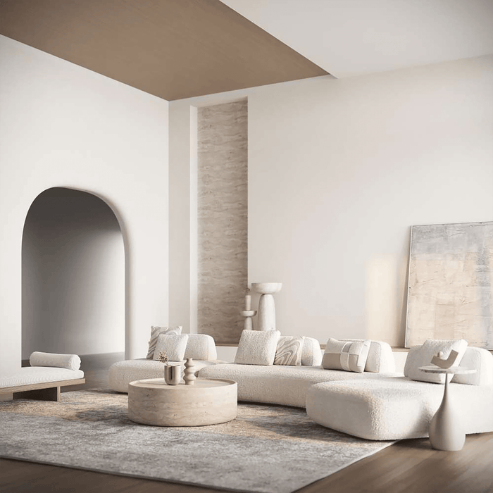 Modern living room with a curved white sofa, coffee table, and decorative pillows.