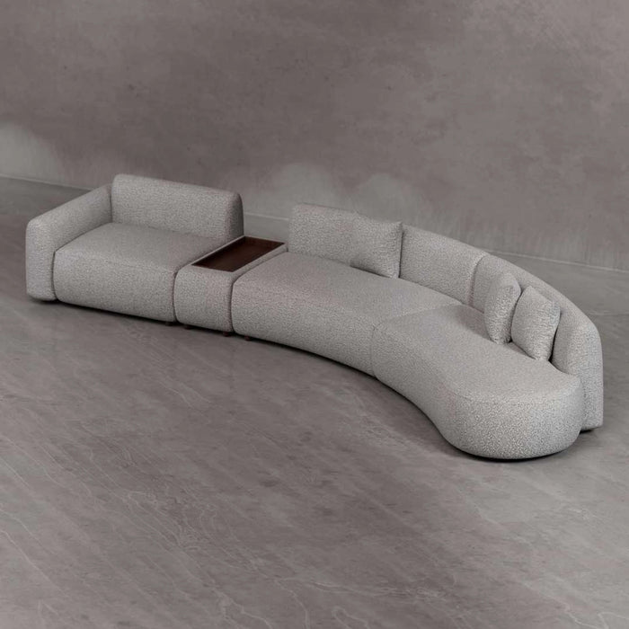 Modern gray sofa with a wooden table insert on a gray floor.