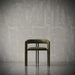 Modern chair with a metallic finish against a textured gray wall.