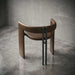 Brown leather stool with black metal legs on a gray concrete floor.