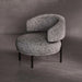 Modern armchair with textured gray upholstery on a dark floor and gray wall background