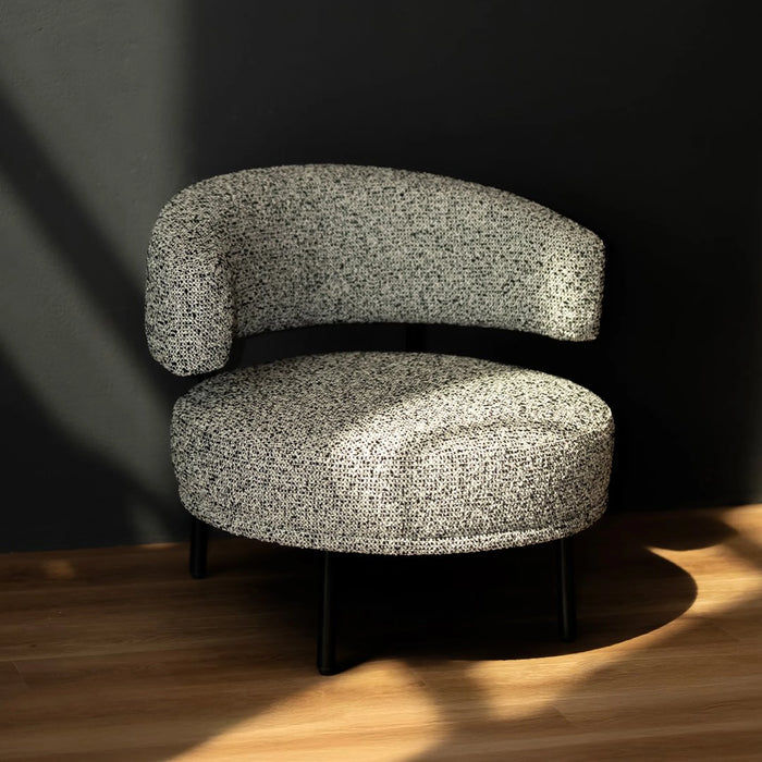Gray textured armchair on a wooden floor with a dark wall background