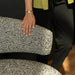 Person sitting on a textured chair with a blurred background