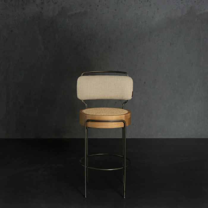 Bar stool with beige cushioned seat and backrest against a dark gray wall