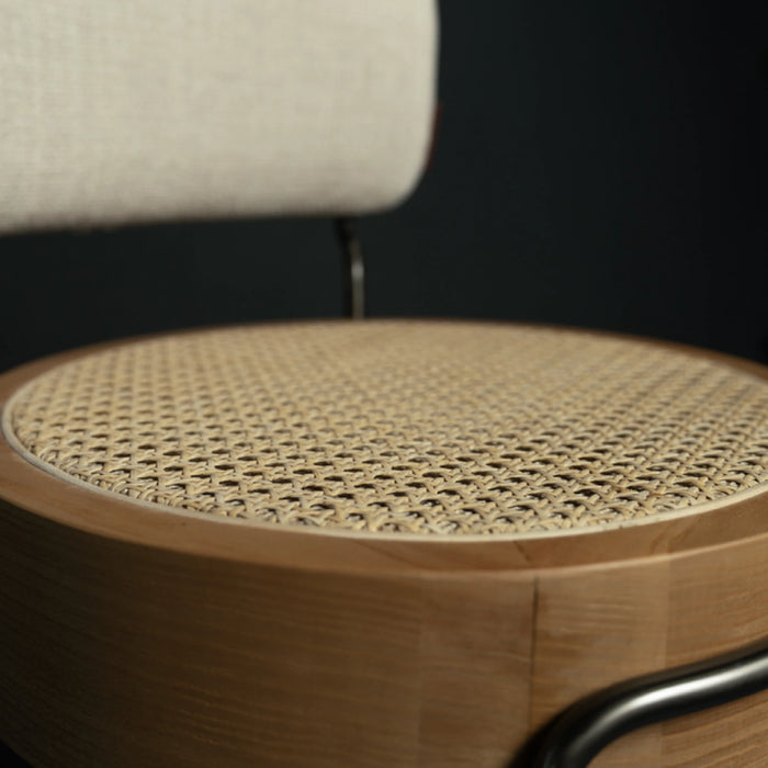 Close-up of a chair with woven seat and wooden frame against a dark background