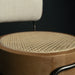 Close-up of a chair with woven seat and wooden frame against a dark background