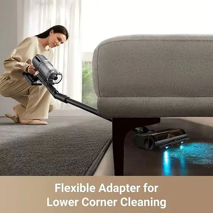 Person using a vacuum cleaner with a flexible adapter to clean under a sofa.